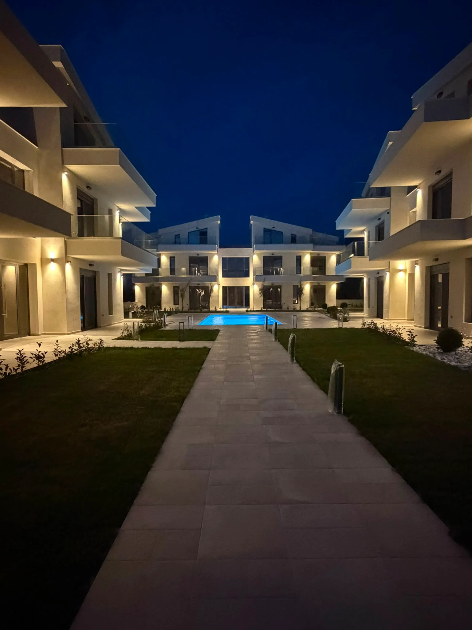 Complexul VRO Real Estate noaptea cu piscină iluminată